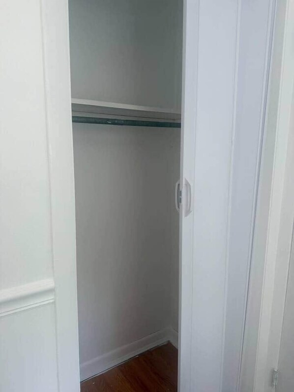 Ein schmaler, weißer Kleiderschrank mit einer einzelnen Ablagefläche.