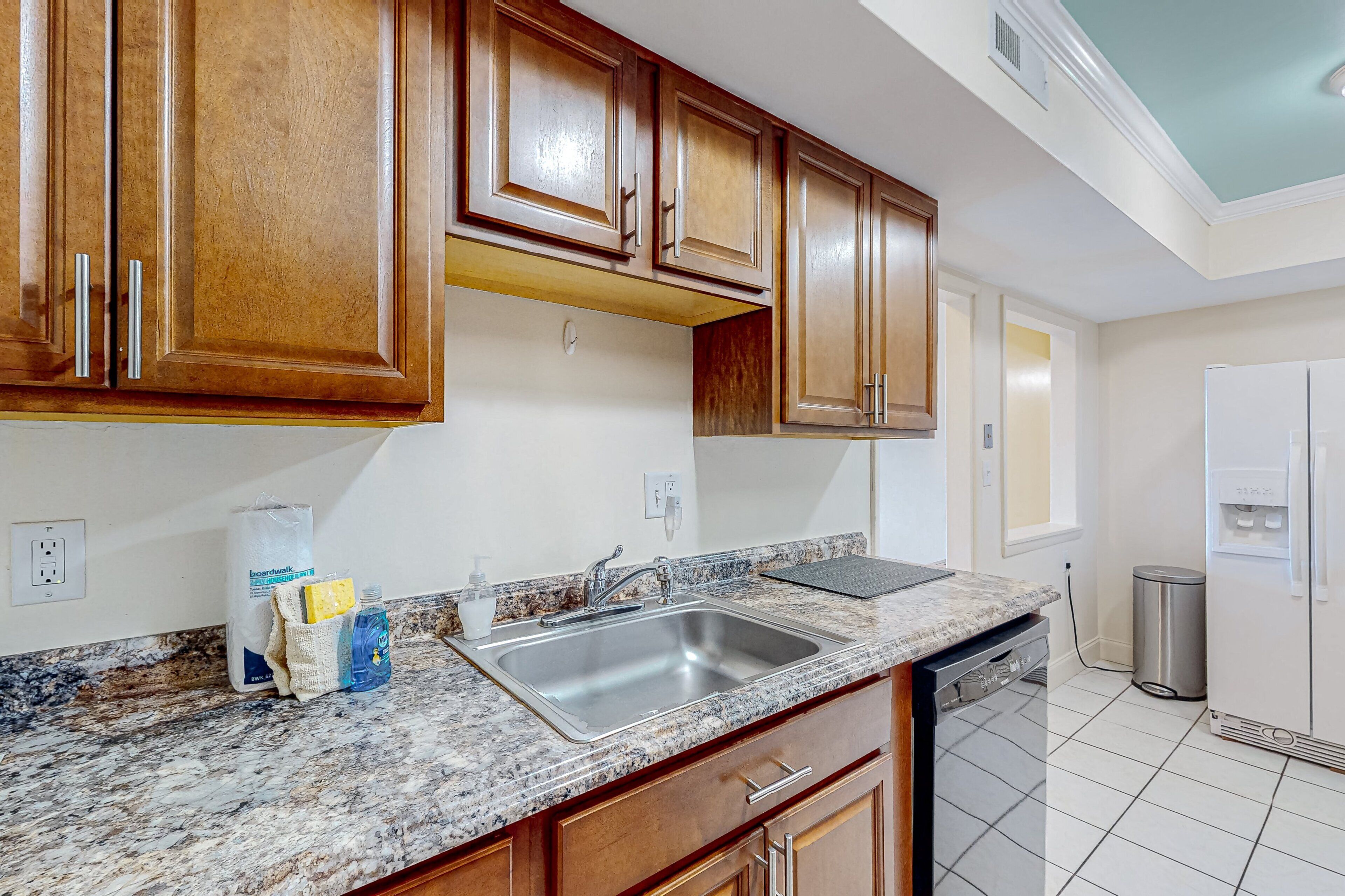 A kitchen with wooden cabinets, a granite countertop, a stainless steel sink, and a dishwasher.