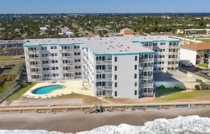 Um hotel com vários andares, piscina e vista para a praia.