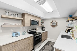 A modern kitchen with built-in appliances, wooden cabinetry, and a central island. - Sandpiper Towers 512 (Satellite Beach)