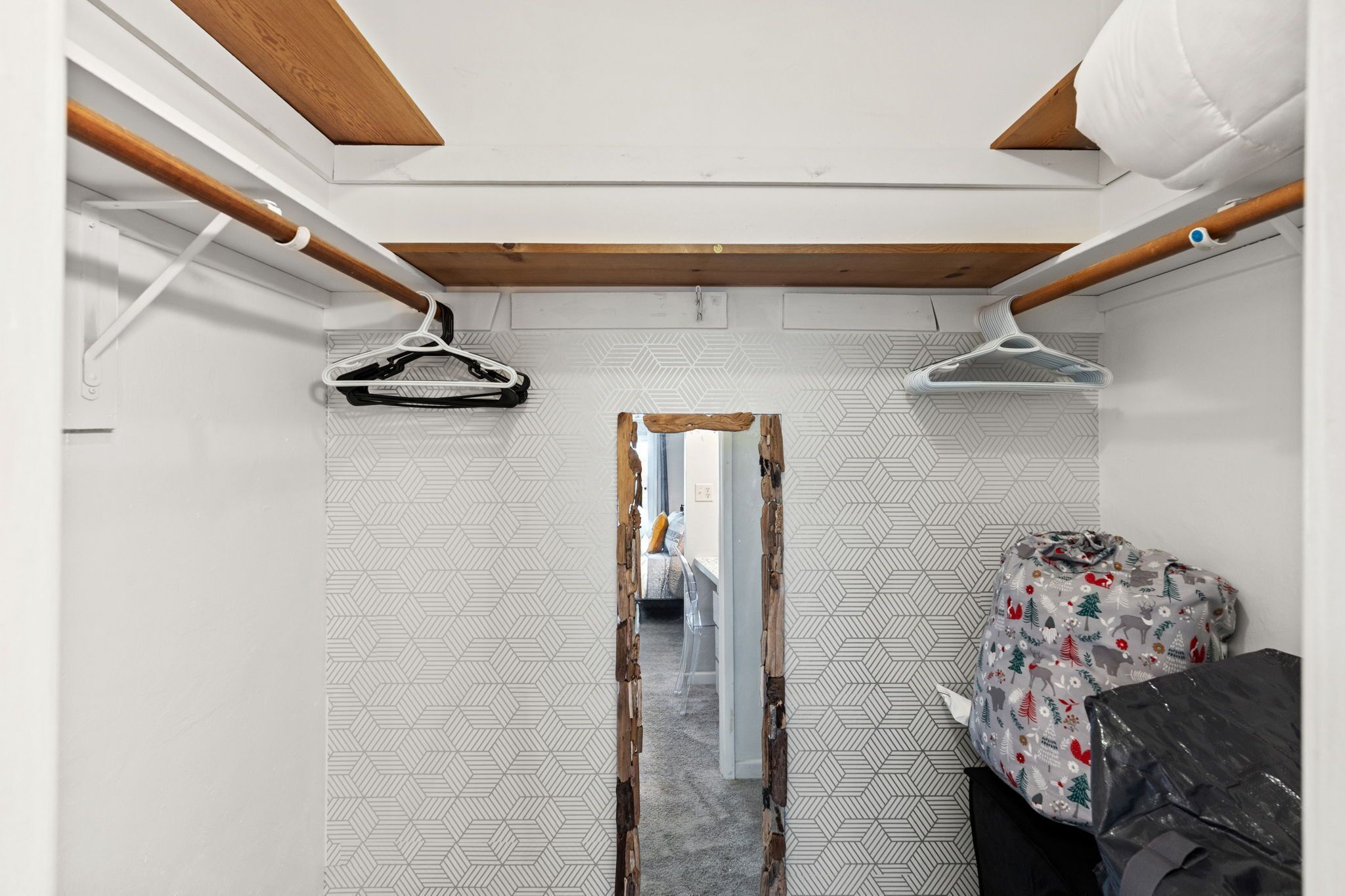 Una stanza compatta con soffitto spiovente, una trave in legno, un appendiabiti sospeso e un muro decorato.