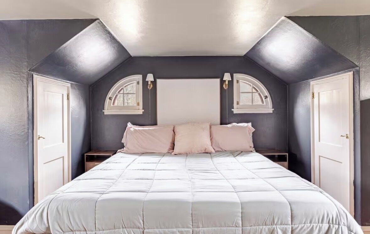 Une chambre à coucher avec un grand lit, deux tables de chevet et une fenêtre à cadre blanc.