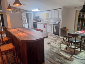 Une cuisine moderne avec un bar en bois, des meubles blancs et une table à manger avec des chaises.