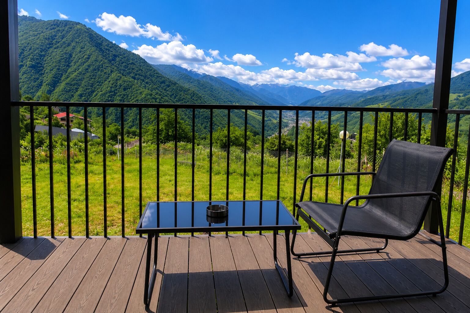 Un balcon avec une table et une chaise, offrant une vue sur des collines verdoyantes et des montagnes.