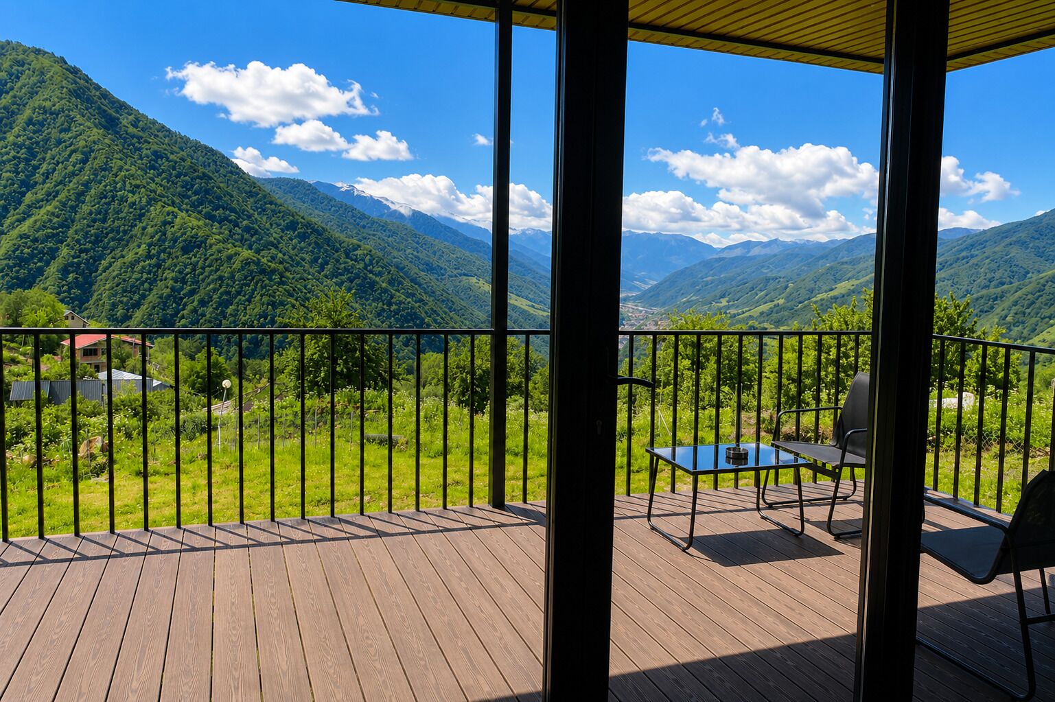 A wooden deck with a table and chairs, overlooking a mountainous landscape with a clear sky.