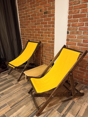 Zwei gelbe Lounge-Sessel vor einer Backsteinwand in einem Raum mit Holzdielen.
