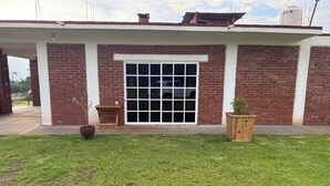 Un bâtiment à l’extérieur en briques, avec une grande porte vitrée et une petite table en bois sur laquelle est posée une plante en pot.