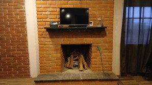 Une cheminée en briques avec un téléviseur au-dessus et un feu de bois qui crépite à l’intérieur.