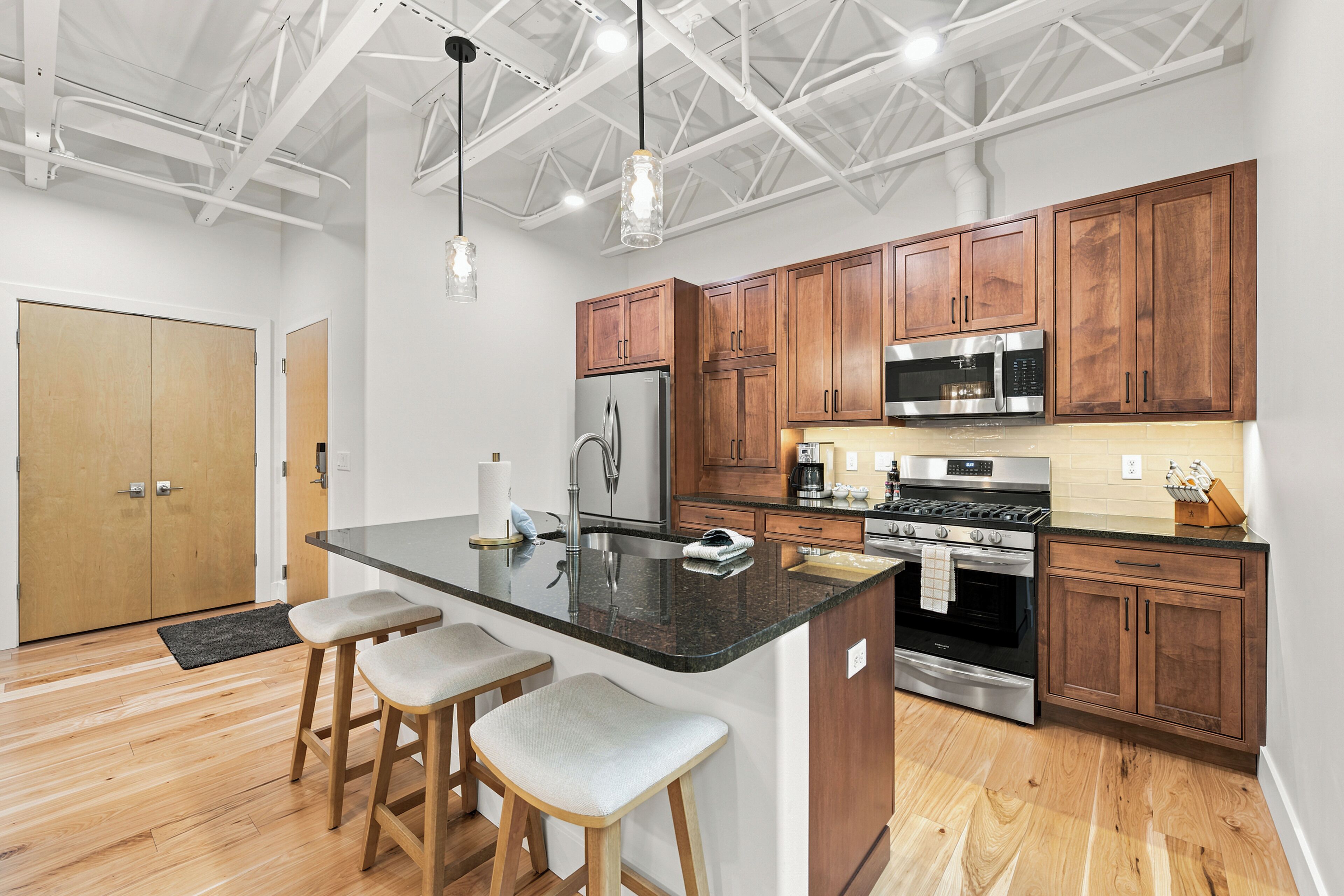A modern kitchen with wooden cabinets, stainless steel appliances, and a central island with bar stools.