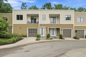 Ein mehrstöckiges Wohnhaus mit Hauseingang, zwei Balkonen und einer Garage.