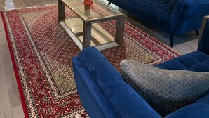 A living room with a blue sofa, a glass coffee table, and a red patterned rug. - Executive Parkside Retreat in Heart of Unionville (Markham)