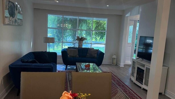 A modern living room with a dining table, a blue sofa, and a chandelier. - Executive Parkside Retreat in Heart of Unionville (Markham)