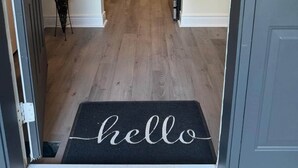 A hallway leading to a dining area with a chandelier, a potted plant, and a 'hello' mat at the entrance. - Executive Parkside Retreat in Heart of Unionville (Markham)