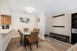 A dining area with a glass table, leather chairs, a wooden bench, and a wall-mounted shelf. - Park Station Condo in Old Town Park City | Walk to Town Lift, No Stairs + Heated Pool! (Park City)