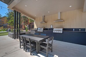 Une cuisine extérieure équipée d’un barbecue, d’une table à manger et de chaises.