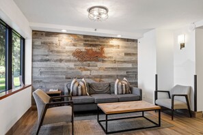 A modern living room with a wooden wall, a sofa, two armchairs, a coffee table, and a side table. - Park Station Condo in Old Town Park City | Walk to Town Lift, No Stairs + Heated Pool! (Park City)