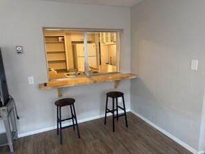 Cocina con encimera de madera, dos taburetes y un espejo que refleja el interior.