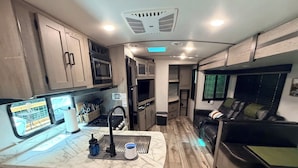Cucina compatta per camper, con fornello, lavello e microonde.