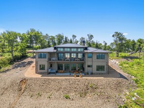 A modern two-story house with a balcony, large windows, and a patio area. - High View: Brand-New 5,100 Sq Ft Nordic-Inspired Mountain Estate with Four-State Views (Banner Elk)