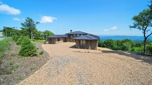 A house with a gravel driveway, a covered patio, and a view of the landscape. - High View: Brand-New 5,100 Sq Ft Nordic-Inspired Mountain Estate with Four-State Views (Banner Elk)