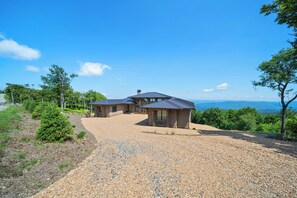 Ein Haus mit Kiesweg, einer überdachten Terrasse und Blick auf die Landschaft.