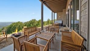 An outdoor patio with wooden furniture, a fire pit, and a view of the landscape. - High View: Brand-New 5,100 Sq Ft Nordic-Inspired Mountain Estate with Four-State Views (Banner Elk)