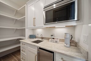 A modern kitchen with white cabinetry, a stainless steel microwave, a coffee maker, and a toaster. - High View: Brand-New 5,100 Sq Ft Nordic-Inspired Mountain Estate with Four-State Views (Banner Elk)