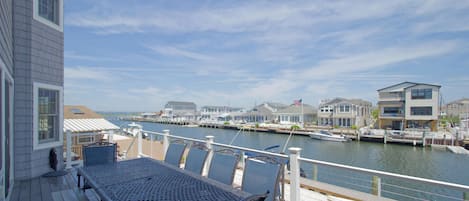 A deck with a table and chairs overlooking a marina with boats and houses.