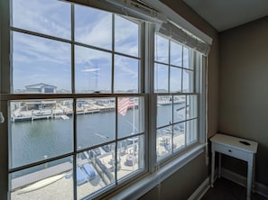 A room with a large window overlooking a marina, a small table, and a view of boats and docks. - Family friendly Lagoon front 2 blocks to ocean.
8 Beach Badge. 
3 TV Beach Chair (Lavallette)