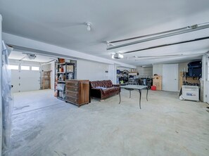 Eine geräumige Garage mit einer braunen Ledersofa, einer Holzkommode und einem Tisch.