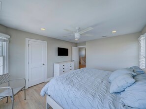 A bedroom with a bed, a chair, a dresser, a television, and a ceiling fan. - Family friendly Lagoon front 2 blocks to ocean.
8 Beach Badge. 
3 TV Beach Chair (Lavallette)