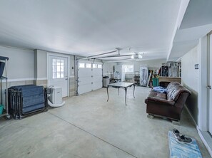 A spacious garage with a dining table, a brown leather couch, and a shoe rack. - Family friendly Lagoon front 2 blocks to ocean.
8 Beach Badge. 
3 TV Beach Chair (Lavallette)