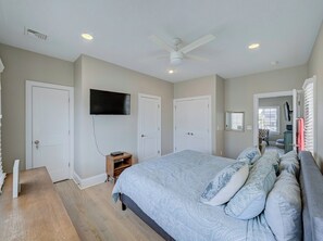 Ein Schlafzimmer mit einem Bett, einem an der Wand montierten Fernseher und einem Deckenventilator.