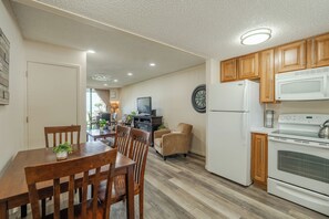 Eine moderne Küche mit Holzschränken, einem weißen Kühlschrank, einer Mikrowelle und einem Herd.