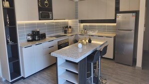 A modern kitchen with a built-in microwave, a stainless steel refrigerator, and a granite countertop.