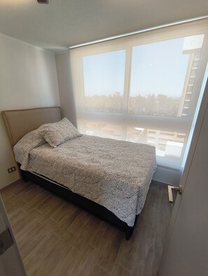 A bedroom with a bed, a window, and a view of the outside.