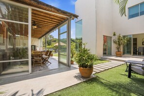 Una casa moderna con un porche cubierto, comedor y césped bien cuidado.