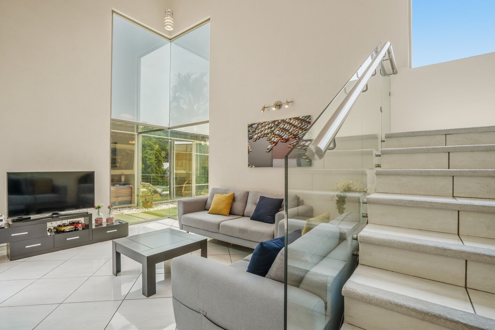 Una sala de estar moderna con televisor, sofá, mesa de centro y escalera.