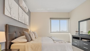 A modern bedroom with a large bed, a nightstand, a dresser, and a window. - Casa Mamino Pool Palapa & Pet Friendly (Cuernavaca)