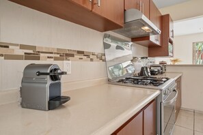 Una cocina con estufa integrada, cafetera y licuadora sobre la encimera.
