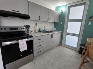 Eine Küche mit Herd, Backofen, Spüle und Schränken.