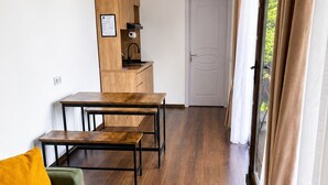 En moderne stue med et træspisebord, en grøn sofa og et køkken med indbygget ovn.