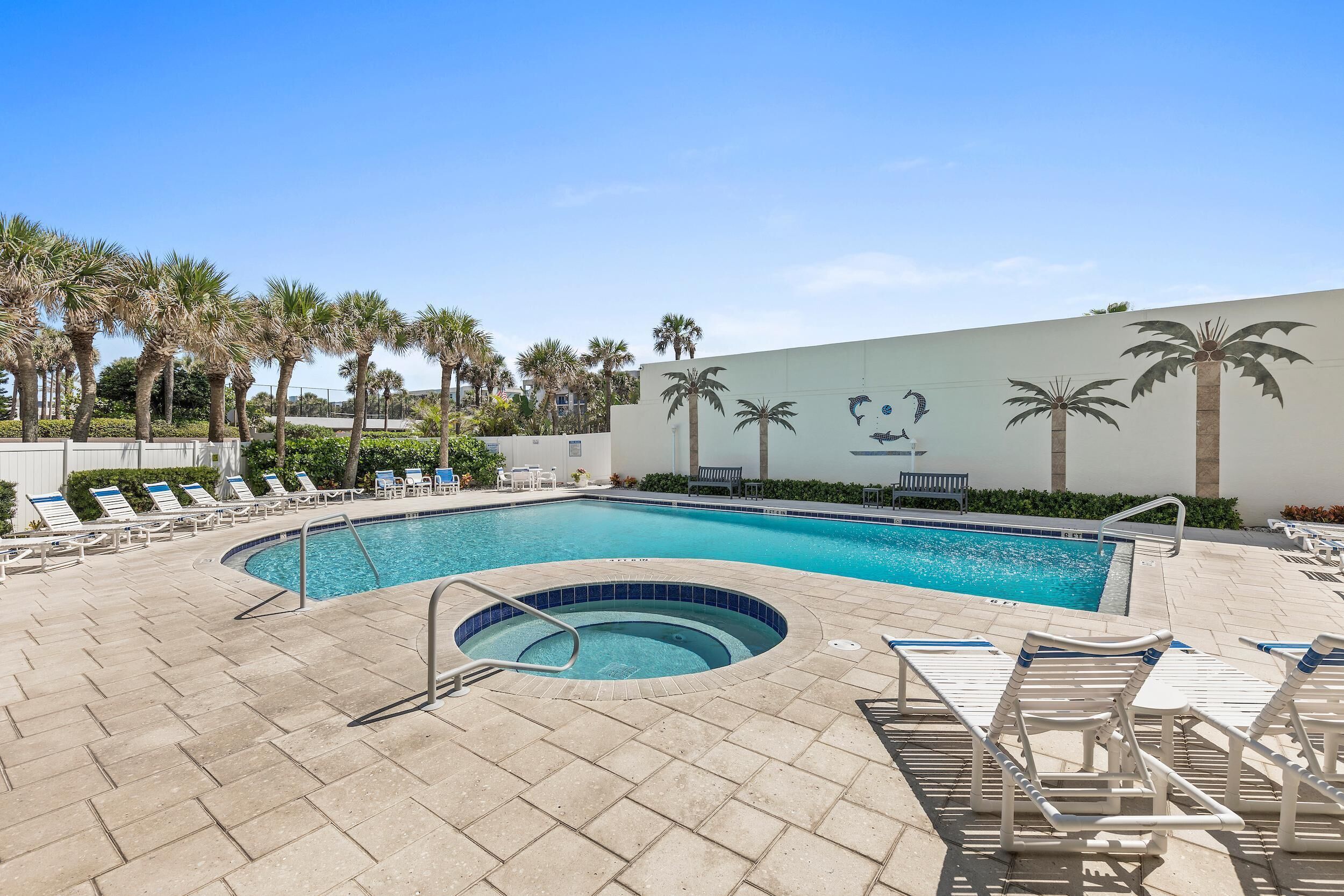 A swimming pool with lounge chairs and palm trees.