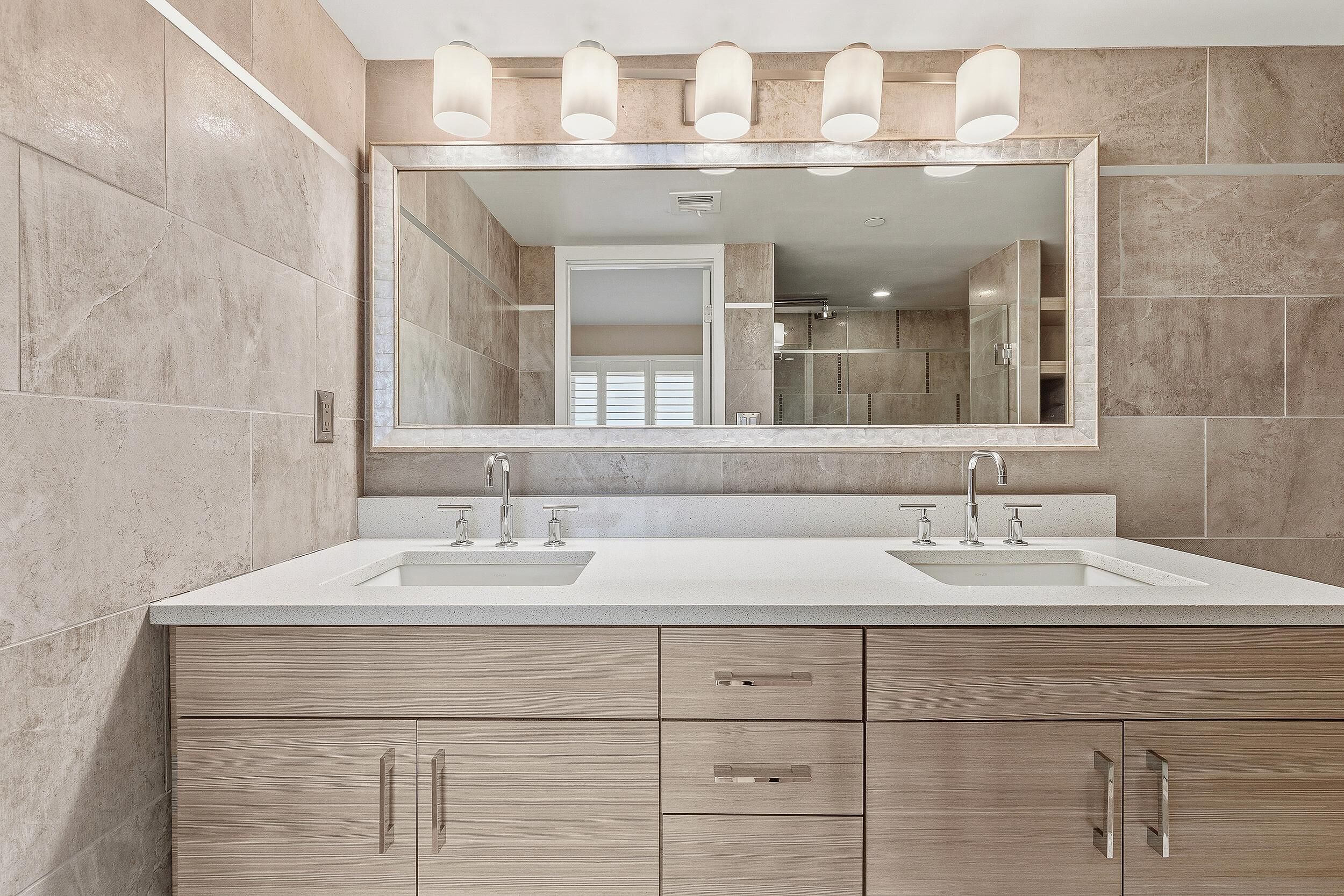 Un baño moderno con dos lavamanos, un espejo grande y una ducha a ras de suelo.