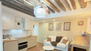 A modern kitchen with wooden beams, a white sofa, and a dining area. - Luxury Stay I Designer Duplex near Bastille (Paris)