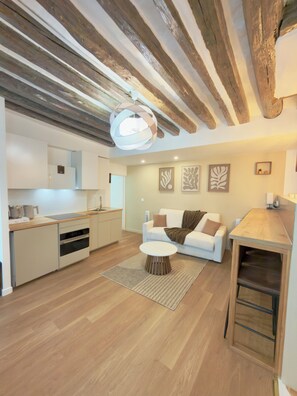 Eine moderne Küche mit Holzbalken, einem weißen Sofa und einem Essbereich.