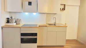 A compact kitchen with a built-in oven, a sink, and a microwave. - Luxury Stay I Designer Duplex near Bastille (Paris)
