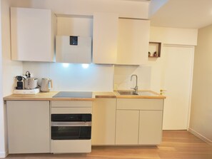 Eine kleine Küche mit Backofen, Spüle und Mikrowelle.