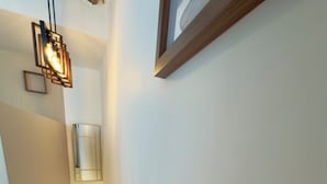 A staircase with a modern design, a wall-mounted light fixture, and a framed picture. - Luxury Stay I Designer Duplex near Bastille (Paris)