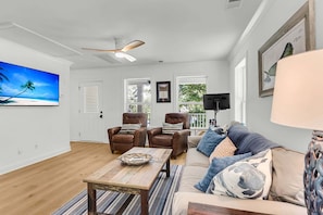 Ein Wohnzimmer mit Deckenventilator, Fernseher, Sofa und Couchtisch.